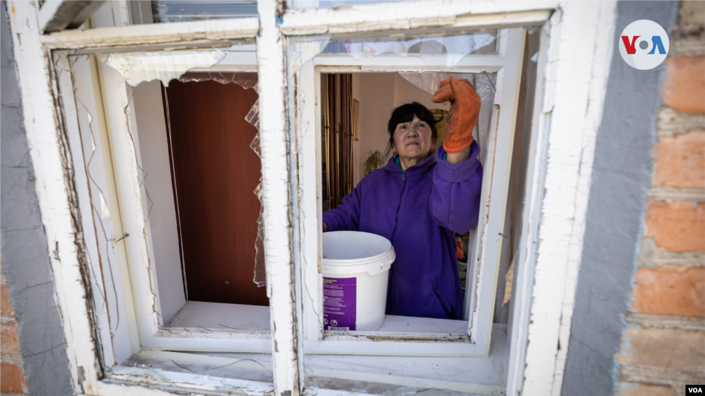 Mujer quita partes del vidrio de la ventana en una casa privada, después de un ataque aéreo ruso al distrito civil en Zaporiyia.