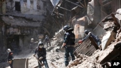 Empleados del Ministerio de Situaciones de Emergencia de la República Popular de Donetsk limpian los escombros al costado del edificio del teatro Mariupol dañado durante los intensos combates en Mariupol, en territorio bajo el gobierno de la República Popular de Donetsk, este de Ucrania, el 1 de mayo de 2022.