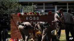 Dos policías de Texas encienden una vela en la Escuela Primaria Robb en Uvalde, Texas, el miércoles 25 de mayo de 2022. (Foto AP/Jae C. Hong)