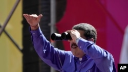El presidente venezolano Nicolás Maduro mira a través de unos binoculares durante un mitin por el Día del Trabajo el domingo 1 de mayo de 2022, en Caracas, Venezuela. (AP Foto/Ariana Cubillos)
