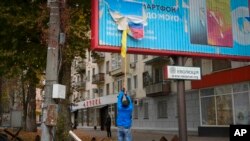 Një banor duke hequr një flamur rus në Kherson