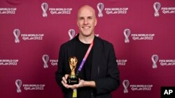 Grant Wahl sonríe mientras sostiene una réplica del trofeo de la Copa Mundial durante una ceremonia en Doha, Qatar, el 29 de noviembre de 2022. (Brendan Moran, FIFA vía AP)