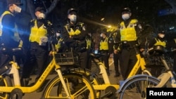Los oficiales de policía montan guardia durante una manifestación contra las restricciones por COVID-19 luego del mortal incendio de Urumqi, en Shanghái, China, el 27 de noviembre de 2022.