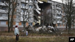 Una mujer pasa frente a un edificio de apartamentos dañado por los bombardeos rusos en Bakhmut, el lugar de las batallas más duras con las tropas rusas, en la región de Donetsk, Ucrania, el 11 de diciembre de 2022.