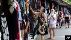 Turis asing berbelanja oleh-oleh di Bali pada Sabtu, 12 November 2022. (Foto: AP)