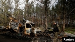 Un oficial del ejército ucraniano camina cerca de los restos de coches destrozados en Lyman, en la región de Donetsk, en octubre de 2022.