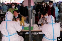 Trabajadores sanitarios atienden a ciudadanos que se realizan pruebas de COVID-19, en Guangzhou, en la provincia sureña china de Guangdong, el 25 de marzo de 2022.