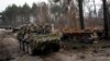 Soldados ucranianos captados el 31 de marzo mientras transitaban sobre vehículos blindados junto a un tanque ruso destruido en las afueras de Kiev. Alemania y otros países europeos refuerzan la ayuda al ejército del país invadido por Rusia.
