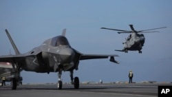 ARCHIVO - Personal militar dirige aviones F-35 y un helicóptero en la cubierta del portaaviones HMS Queen Elizabeth mientras participa en el ejercicio Steadfast Defender 2021 de la OTAN frente a las costas de Portugal, el 27 de mayo de 2021.