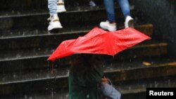 ARCHIVO - Una persona se protege de la lluvia causada por el potencial ciclón tropical dos, a su paso por el Caribe, en Caracas, Venezuela, el 29 de junio de 2022. REUTERS/Leonardo Fernández Viloria