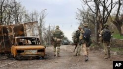 Militares de la milicia de la República Popular de Donetsk pasan junto a vehículos dañados durante un intenso combate en un área controlada por las fuerzas separatistas respaldadas por Rusia en Mariupol, Ucrania, el 19 de abril de 2022.