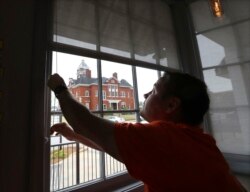 Brian Lambert, dueño de Scoops, una tienda de café y dulces, abre las ventanas de su negocio en Forsyth, Georgia, mientras se prepara para reabrir la próxima semana.