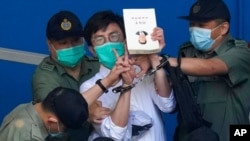 El activista prodemocracia Avery Ng, centro, sostiene un libro con una imagen de portada del presidente chino, Xi Jinping, mientras es trasladado a un tribunal en Hong Kong, el 28 de mayo de 2021.