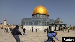 Un camarógrafo cae el suelo perseguido por un policía isralí durante enfrentamientos en el complejo de la mezquita de al-Aqsa en Jerusalén el 10 de mayo de 2021.