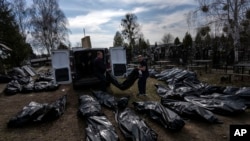 Trabajadores del cementerio descargan cuerpos de civiles muertos desde una camioneta en el cementerio de Bucha, en las afueras de Kiev, Ucrania, el 7 de abril de 2022.