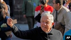 El presidente de México, Andrés Manuel López Obrador, muestra su tarjeta de identificación después de votar en un referéndum sobre si debe terminar su mandato de seis años o continuar hasta el final, en la Ciudad de México, el domingo 10 de abril. 2022. (Foto AP/Eduardo Verdugo)