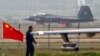 A China-made J-31 stealth fighter (background) lands on a runway after a flying performance at the China International Aviation and Aerospace Exhibition in Zhuhai, Guangdong province, Nov. 11, 2014.