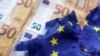 ARCHIVO - La ilustración muestra billetes de euros y una bandera rota de la Unión Europea.
