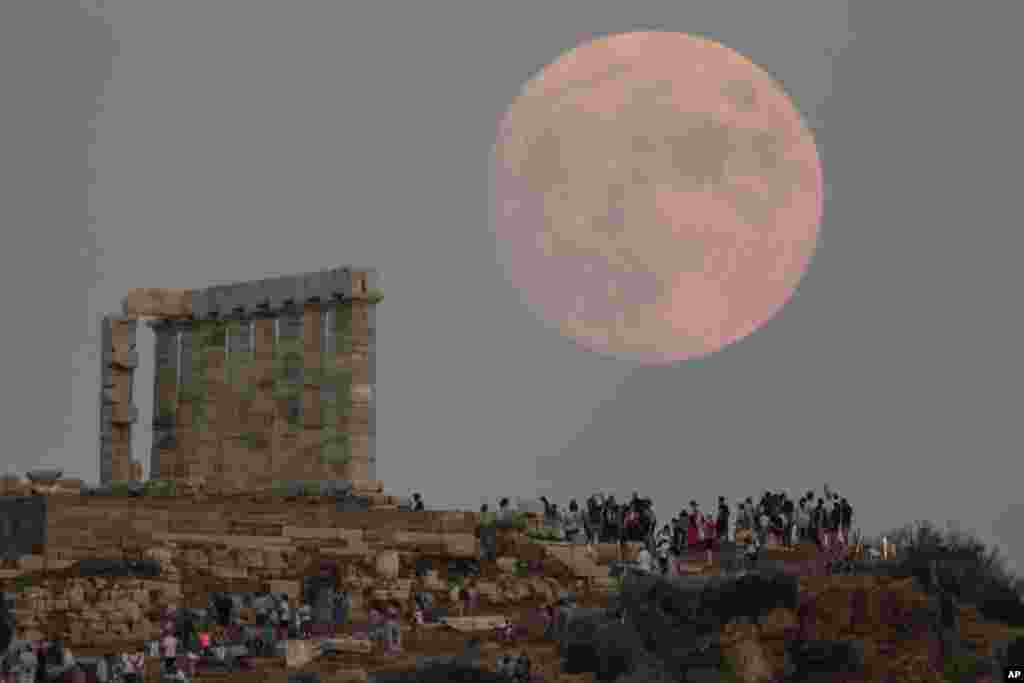 The moon rises behind the columns of the ancient marble Temple of Poseidon at Cape Sounion, about 70 Km (45 miles) south of Athens, Greece, Aug. 2, 2020.
