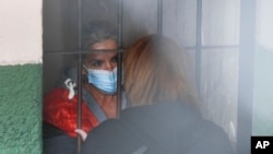 Tras las rejas, la expresidenta interina de Bolivia, Jeanine Áñez, habla con una mujer no identificada en la cárcel de una comisaría en La Paz, Bolivia, el 13 de marzo de 2021. 