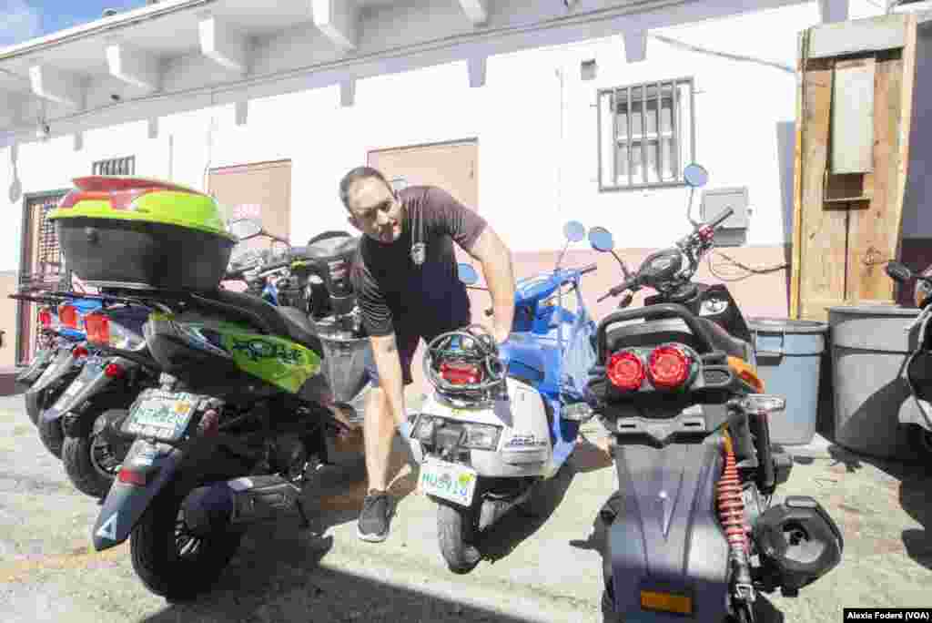 El cubano José Blanco trabaja en un scooter en la trastienda de El Rey de las Motos, el 25 de enero de 2023. Blanco, recién llegado a Estados Unidos, es uno de los cientos de migrantes que usa este medio de transporte asequible para moverse en Miami.&nbsp;