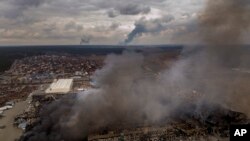 Una fábrica y una tienda arden tras ser bombardeadas en Irpin, en las afueras de Kiev, Ucrania, el domingo 6 de marzo de 2022. [Foto AP/Emilio Morenatti]