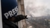 El fotógrafo de Associated Press Evgeniy Maloletka señala el humo que se eleva después de un ataque aéreo en un hospital de maternidad, en Mariupol, Ucrania, el miércoles 9 de marzo de 2022. [Foto AP/Mstyslav Chernov]