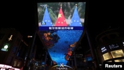 Una pantalla gigante muestra imágenes de noticias de banderas nacionales chinas y banderas de la Unión Europea durante una cumbre virtual UE-China, en Beijing, China, el 1 de abril de 2022.