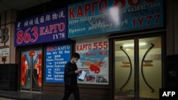 ARCHIVO - Un hombre pasa frente a una tienda que anuncia envíos de carga a Rusia y otros países, en una calle de Beijing, el 4 de marzo de 2022.