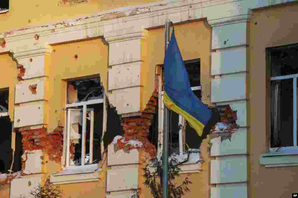Una bandera ucraniana ondea frente a un edificio dañado por los bombardeos en Kharkiv, Ucrania, el viernes 11 de marzo de 2022. (Foto AP/Andrew Marienko)