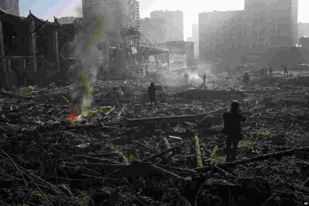 Gente reunida entre los restos de un ataque a un centro comercial en Kiev, Ucrania, el lunes 21 de marzo de 2022. (AP Foto/Rodrigo Abd)