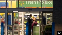 Una empleada de Walmart, centro, habla con la policía mientras trabajan en la escena de un tiroteo masivo en un Walmart, el miércoles 23 de noviembre de 2022, en Chesapeake, Virginia. (AP Photo/Alex Brandon)