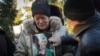 La madre del escritor ucraniano Volodymyr Vakulenko sostiene su foto mientras llora cerca de su tumba durante una ceremonia fúnebre en Kharkiv, Ucrania, el 6 de diciembre de 2022.