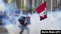 Un simpatizante del destituido presidente Pedro Castillo devuelve un contenedor de gas lacrimógeno en dirección a la policía, el 12 de diciembre de 2022, en Lima, Perú
