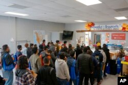 La gente hace fila dentro del centro de bienvenida para inmigrantes frente a la estación de autobuses en Brownsville, Texas, el viernes 16 de diciembre de 2022.