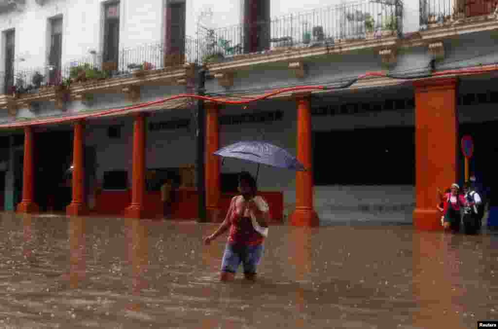 Una mujer camina bajo la lluvia en La Habana, Cuba, que sufrió grandes inundaciones.
