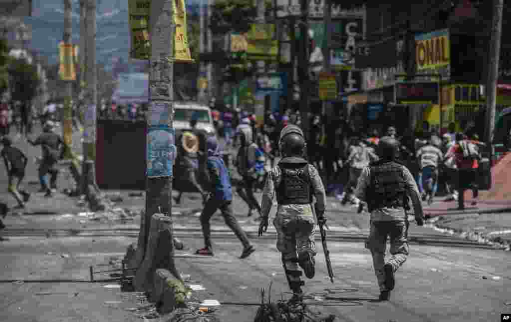 La policía persigue a los saqueadores de un almacén durante una protesta para exigir la renuncia del primer ministro haitiano, Ariel Henry, en Puerto Príncipe, Haití, el jueves 15 de septiembre de 2022.
