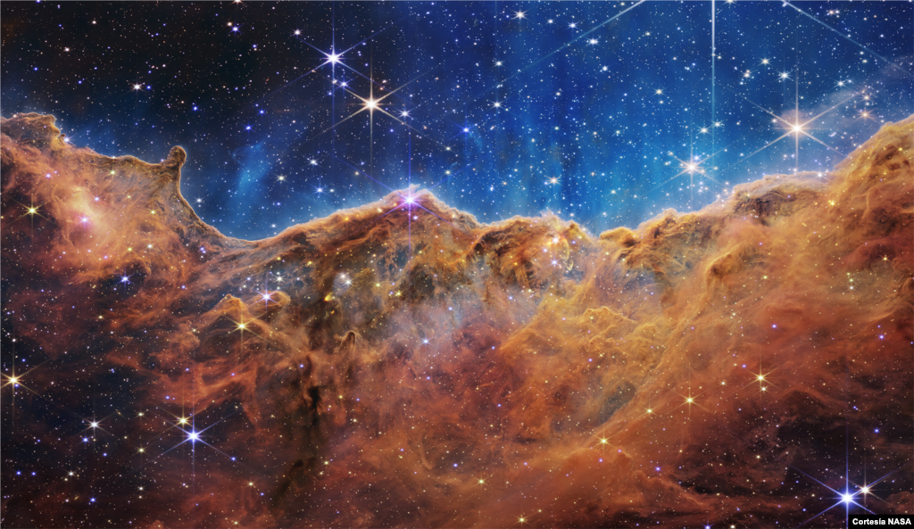 Este panorama de &ldquo;montañas&rdquo; y &ldquo;valles&rdquo; en medio de brillantes estrellas está en el borde de una región próxima y joven de formación de estrellas llamada NGC 3324 en la Nebulosa de Carina. Capturada en luz infrarroja por el telescopio Webb, la imagen revela por primera vez áreas anteriormente invisibles de nacimiento de estrellas.&nbsp;