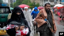 Un combatiente talibán hace guardia mientras la gente camina por el antiguo mercado, en la ciudad de Kabul, Afganistán, el martes 3 de mayo de 2022. (Foto AP/Ebrahim Noroozi)