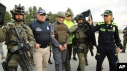 ARCHIVO - En esta foto publicada por la Oficina de Prensa de la Presidencia de Colombia aparece la escolta policial de Dairo Antonio Úsuga, centro, alias "Otoniel", líder del cártel Clan del Golfo antes de su extradición a EEUU en Bogotá, Colombia, el 4 de mayo de 2022. 