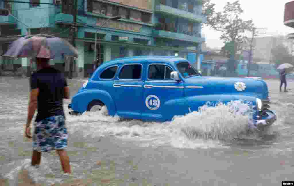 Un auto de alquiler de fabricación estadounidense transita una calle de La Habana, inundada por las fuertes lluvias del 3 de junio de 2022.