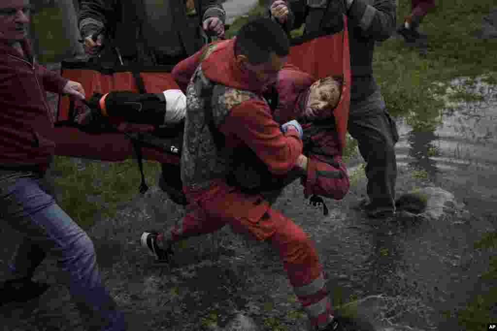 Los habitantes de la localidad ayudan a un trabajador de emergencias a llevar a una ambulancia a un hombre herido al que le falta parte de una pierna tras un bombardeo ruso en Járkiv, Ucrania, el miércoles 27 de abril de 2022. (AP Foto/Felipe Dana)