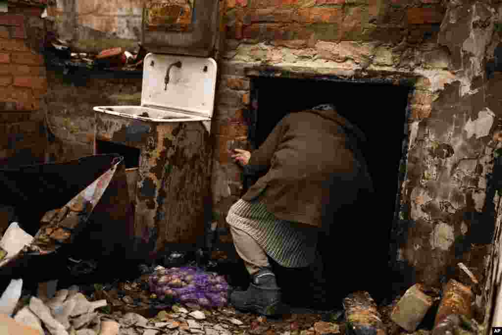 Olena Koptyl, de 63 años, entra en el sótano de su casa destruida tras una batalla entre las tropas rusas y ucranianas en las afueras de Cherníhiv, en el norte de Ucrania, el sábado 23 de abril de 2022. (AP Foto/Francisco Seco)