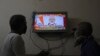Two people watch a televised address to the nation by Prime Minister Narendra Modi on economic stimulus measures, in Hyderabad, India, May 12, 2020.