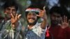 Indian cricket fans react to the camera as they line up to get inside the Chinnaswamy Stadium, the venue of first Twenty20 cricket match between India and Pakistan, in Bangalore, India, Dec. 25, 2012.