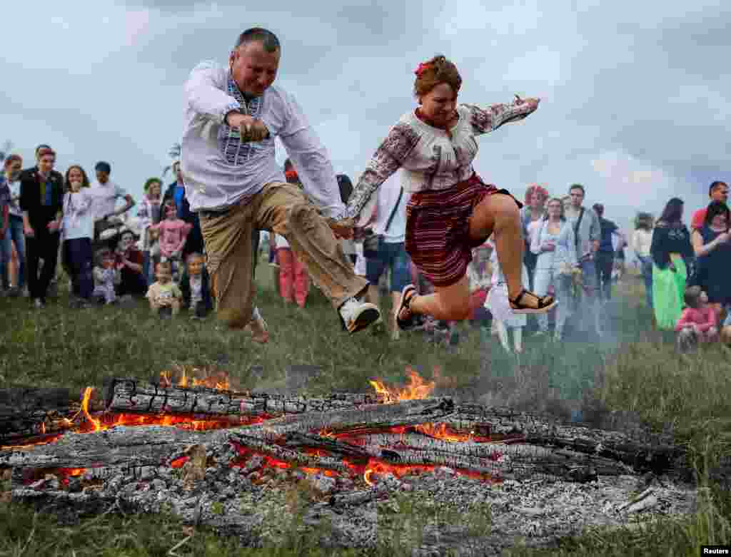 Warga melompati bara api pada festival tradisional Ivana Kupala di Kyiv, Ukraina.