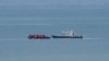 FILE - A boat thought to be carrying migrants is escorted by a vessel from the French Gendarmerie Nationale in the English Channel off Wimereux beach, France, Sept. 4, 2024. 