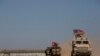 FILE - Turkish and American forces conduct their first joint ground patrol in the so-called "safe zone" on the Syrian side of the border with Turkey, seen in the background, near Tal Abyad, Syria, Sept. 8, 2019.