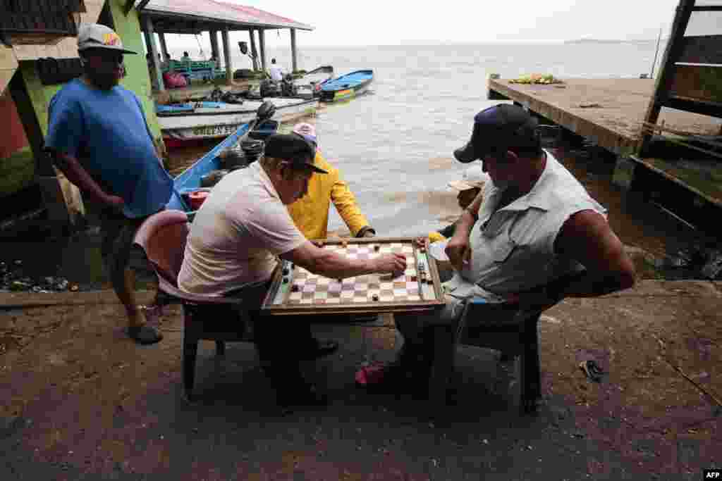 Pescadores juegan tablero -similar a las damas- en el puerto antes de la llegada de la tormenta tropical Bonnie en Bluefields, Nicaragua.&nbsp;