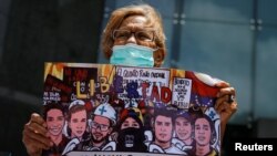 Una mujer sostiene un cartel con imágenes de personas que murieron durante las protestas del 2017, mientras asiste a una manifestación contra los cambios en las sanciones de Estados Unidos en Caracas, el 18 de mayo de 2022.
